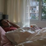Man in bed with a headache.